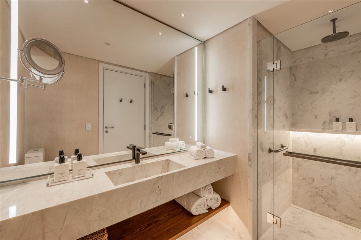 Salle de bains en marbre de The Almer Porto Alegre, douche à l'italienne et produits d'accueil