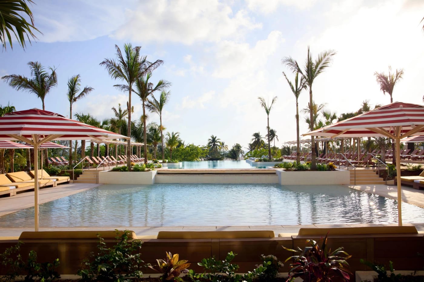 La piscine à débordement et les parasols rayés du Hotel Indigo Grand Cayman, sur Seven Mile Beach