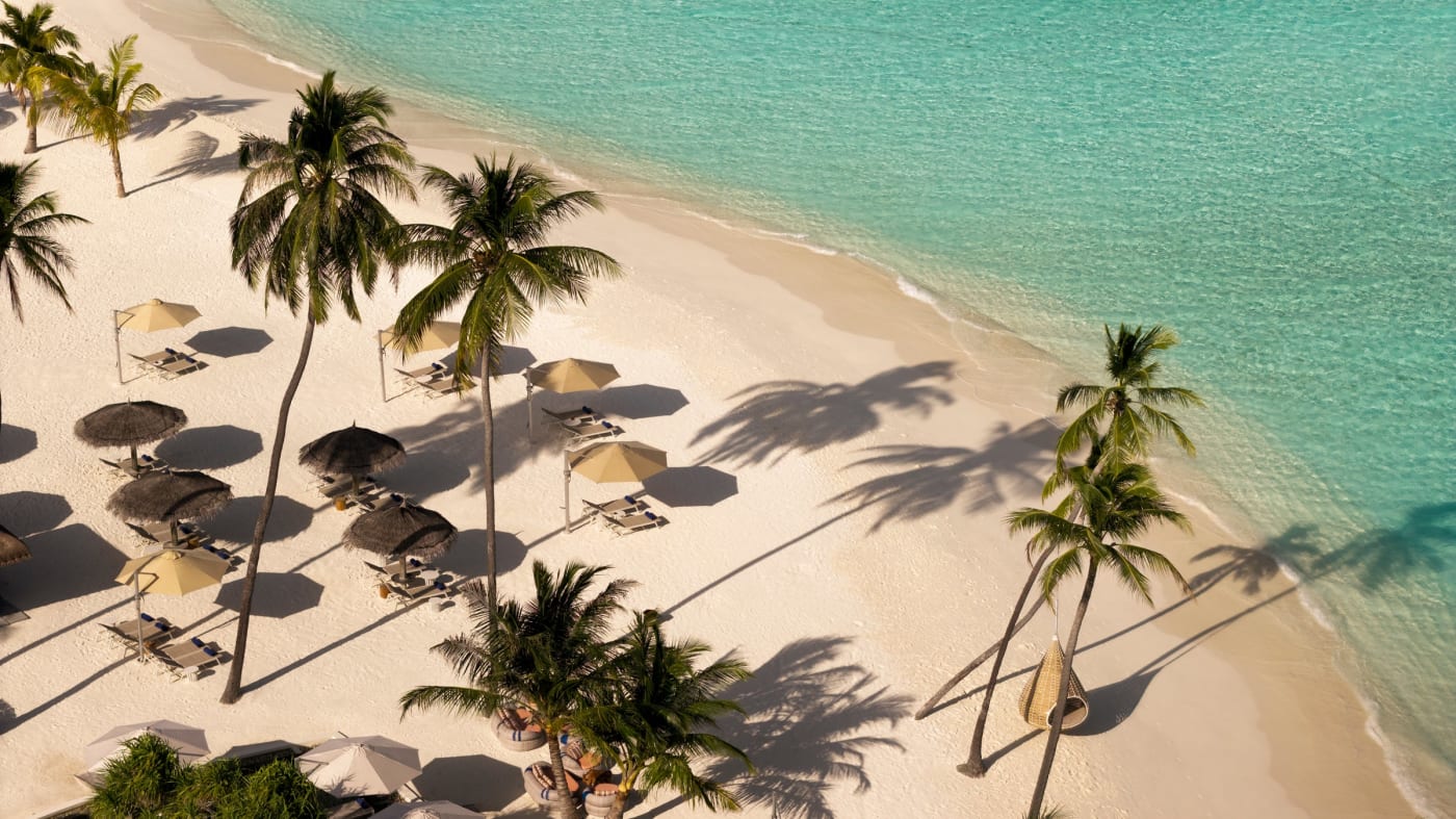 Vista aérea de la playa de arena blanca y las sombrillas del Constance Halaveli Maldives