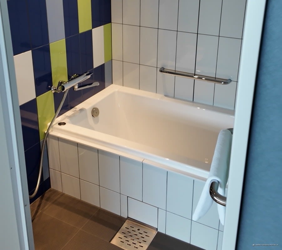 Salle de bain d'une chambre de l'OMO7 Osaka, baignoire profonde et carrelage bleu, blanc et vert