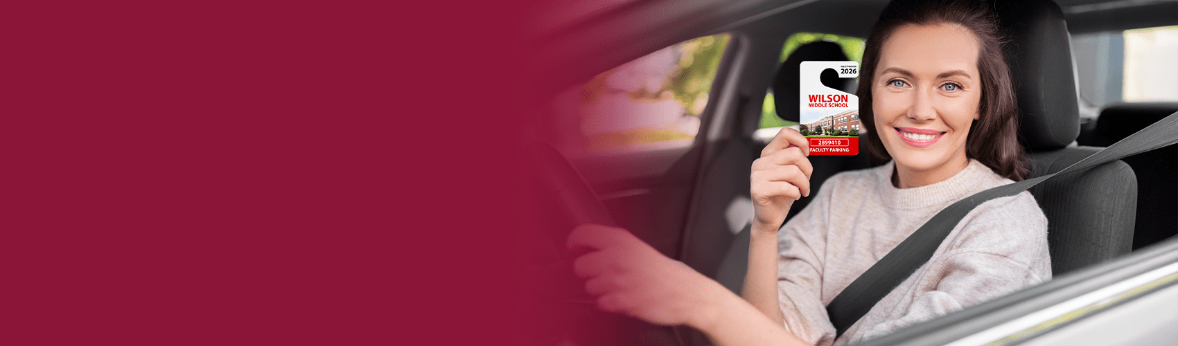 Woman in car holding a school parking permit hang tag