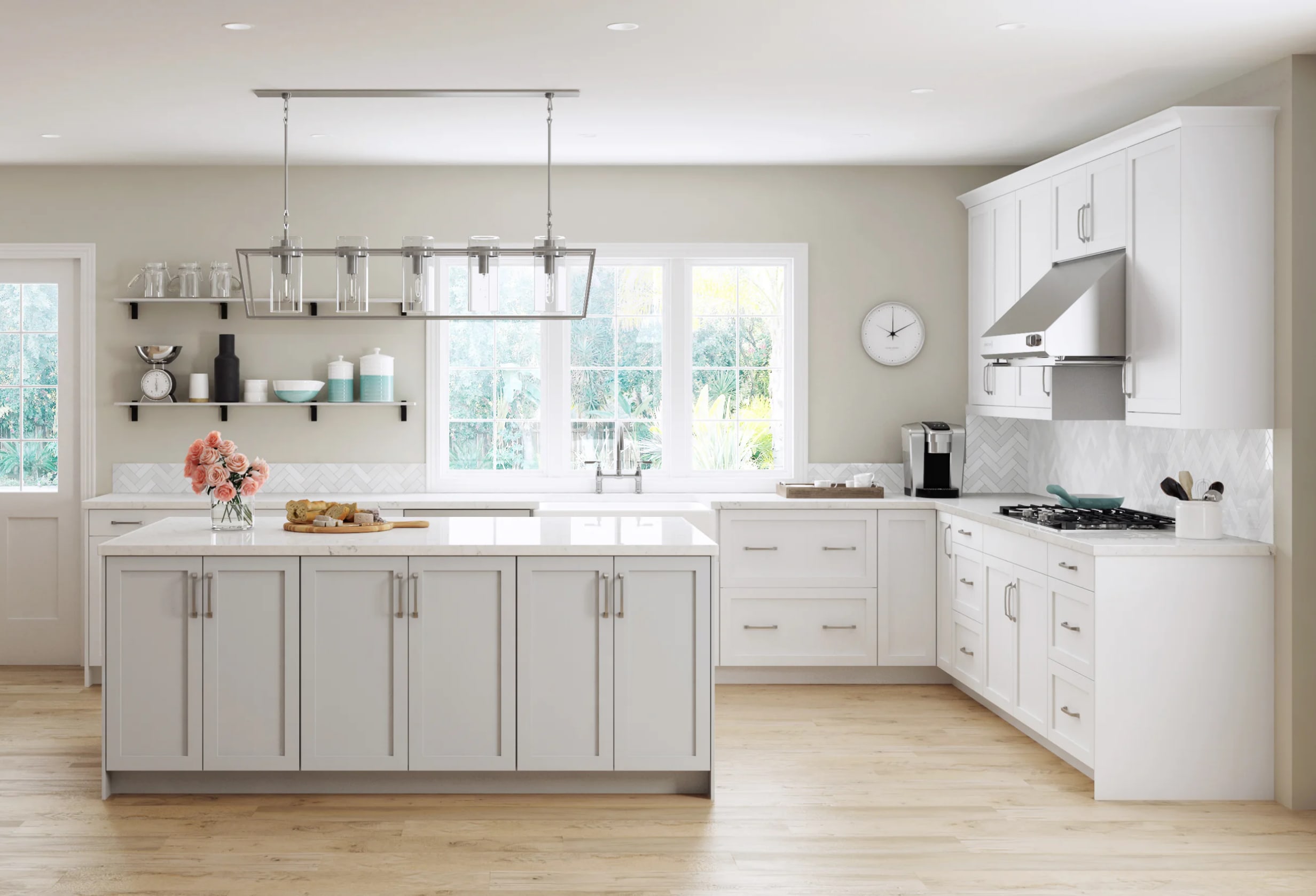 Bright white kitchen with shaker-style cabinets, a spacious island topped in white marble, stainless-steel range and hood, a linear glass-shaded chandelier, open shelves holding dishware and décor, a wall clock, and light wood floors illuminated by large windows.