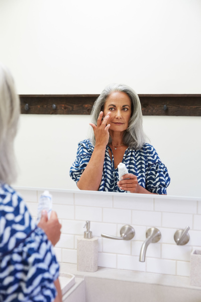 Best anti-aging face masks Woman touching face in mirror