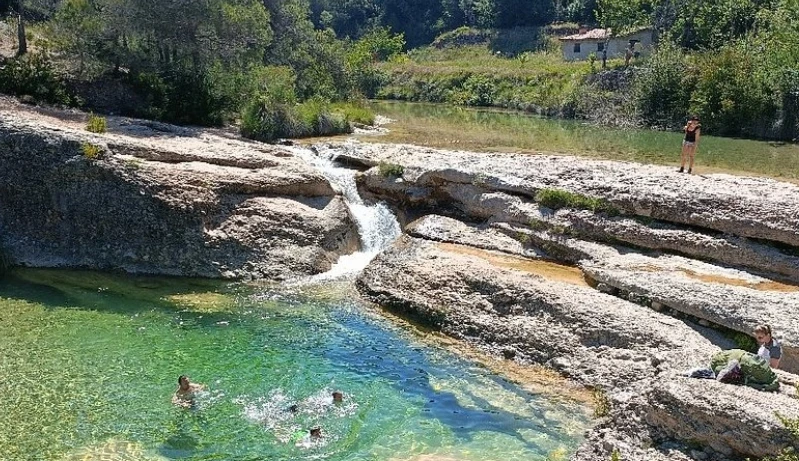 Personas bañándose en aguas cristalinas rodeadas de rocas y naturaleza en las Pesqueras de Beceite