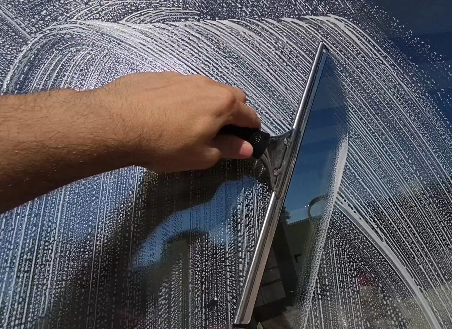 Profesional limpiando cristales de un ventanal grande en Castellón con materiales profesionales