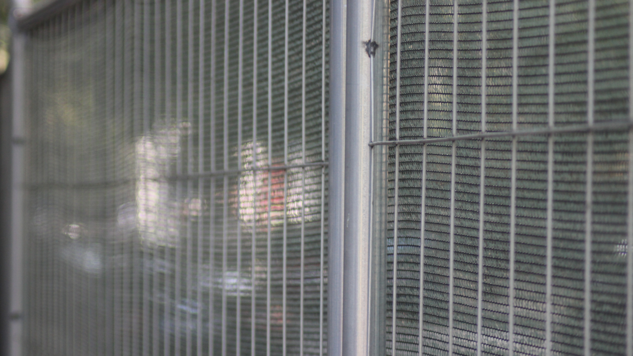 Close view of a fence panel on a construction site secured with anti climb fencing and privacy screening during early spring