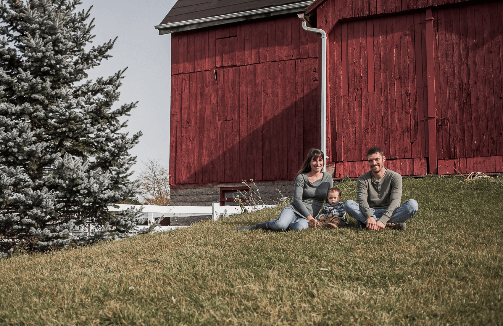 owners with son sitting in front of barn