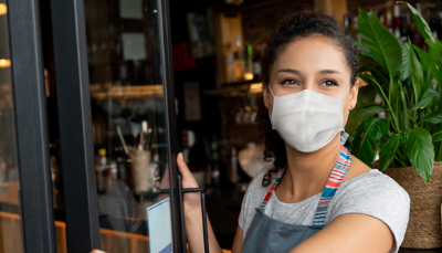 woman with a mask on woman with mask in front of a build - heading 'COVID-19 Resources' and description 'Learn more about service availability, financial relief programs, and more'