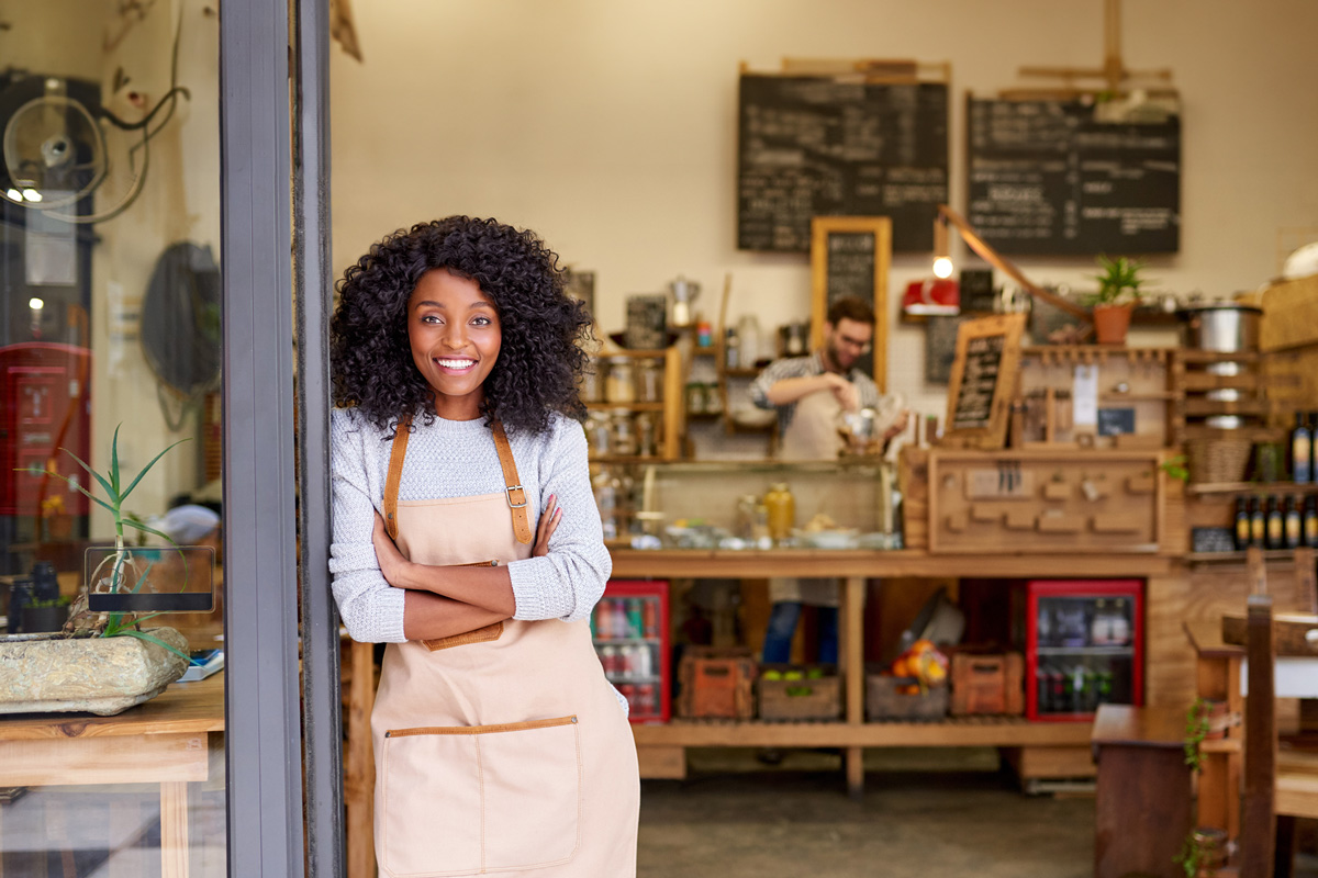 woman leaning against a doorway in front of her business