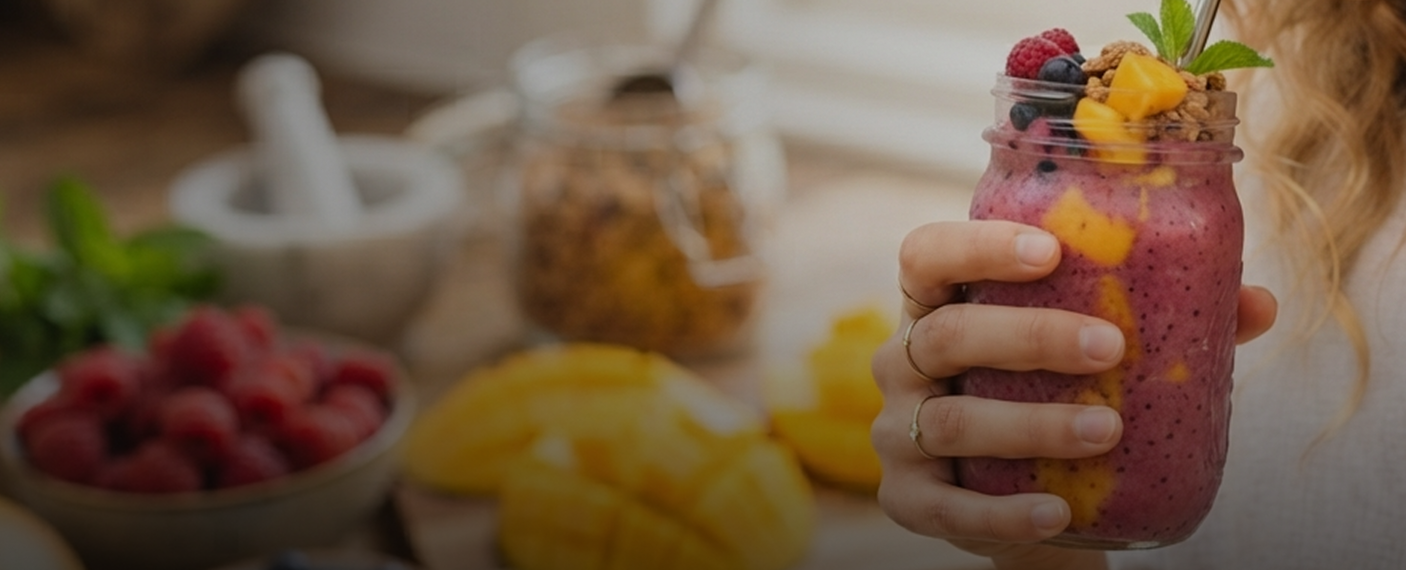 Fresh smoothie bowl held by hand, surrounded by fresh fruit
