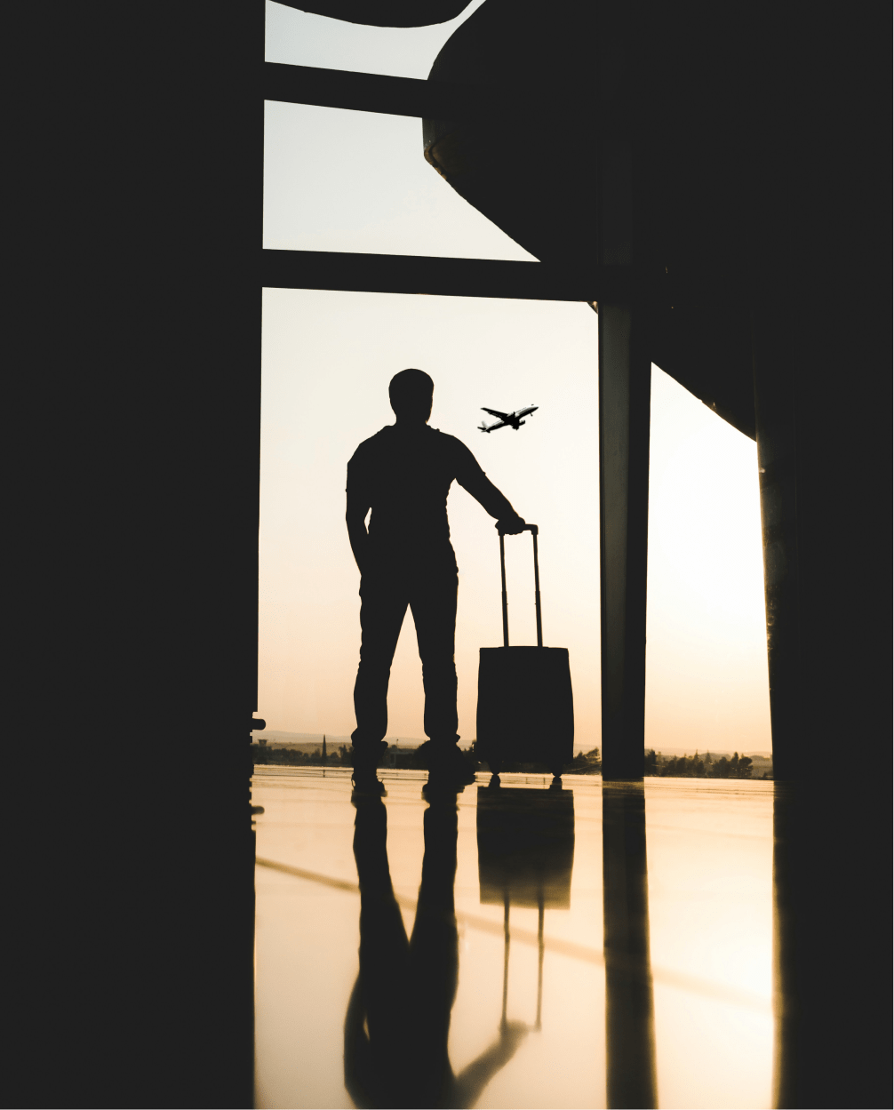 Traveler with suitcase watching an aircraft at sunset