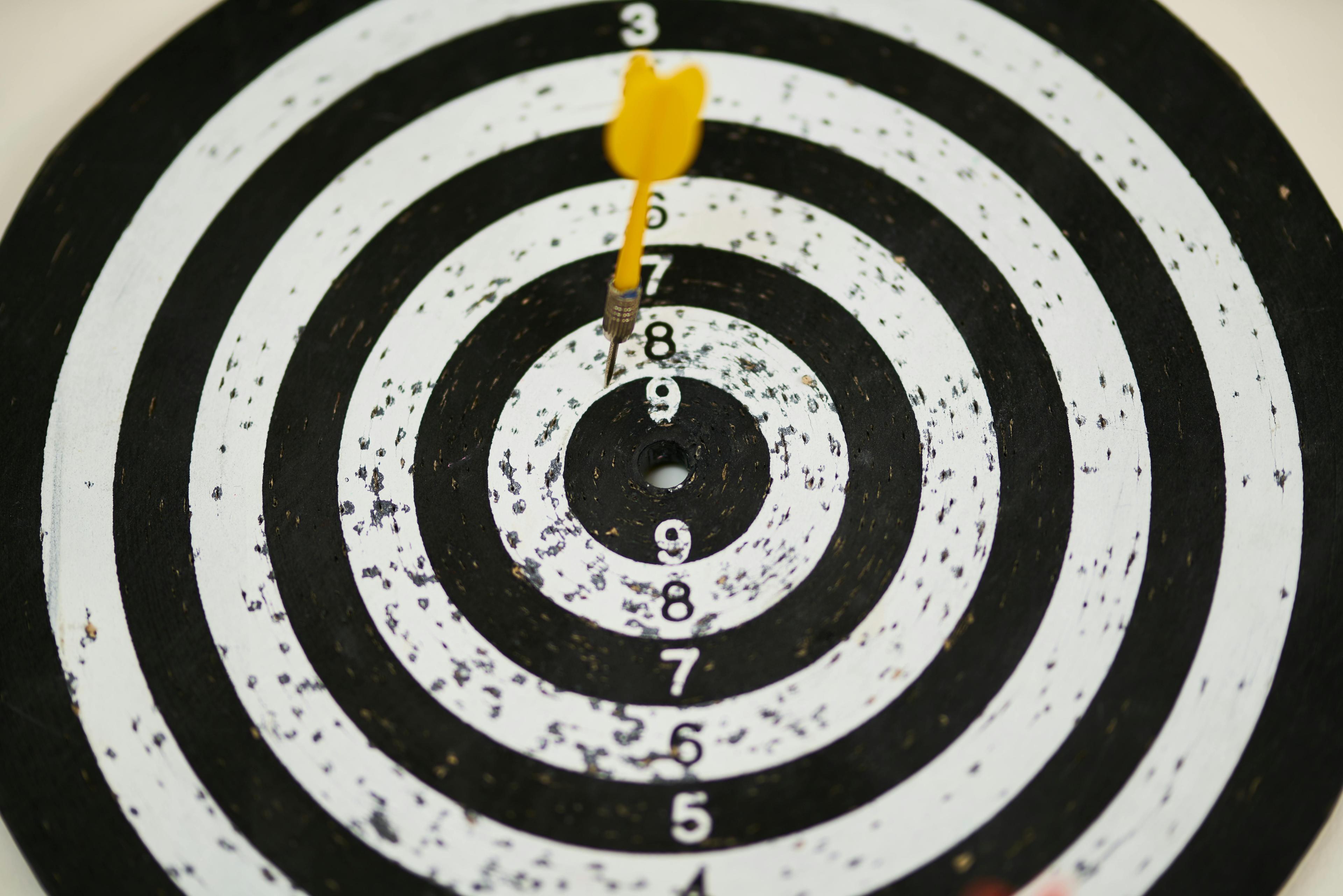 Black and white dart board with a yellow dart hitting the number 8