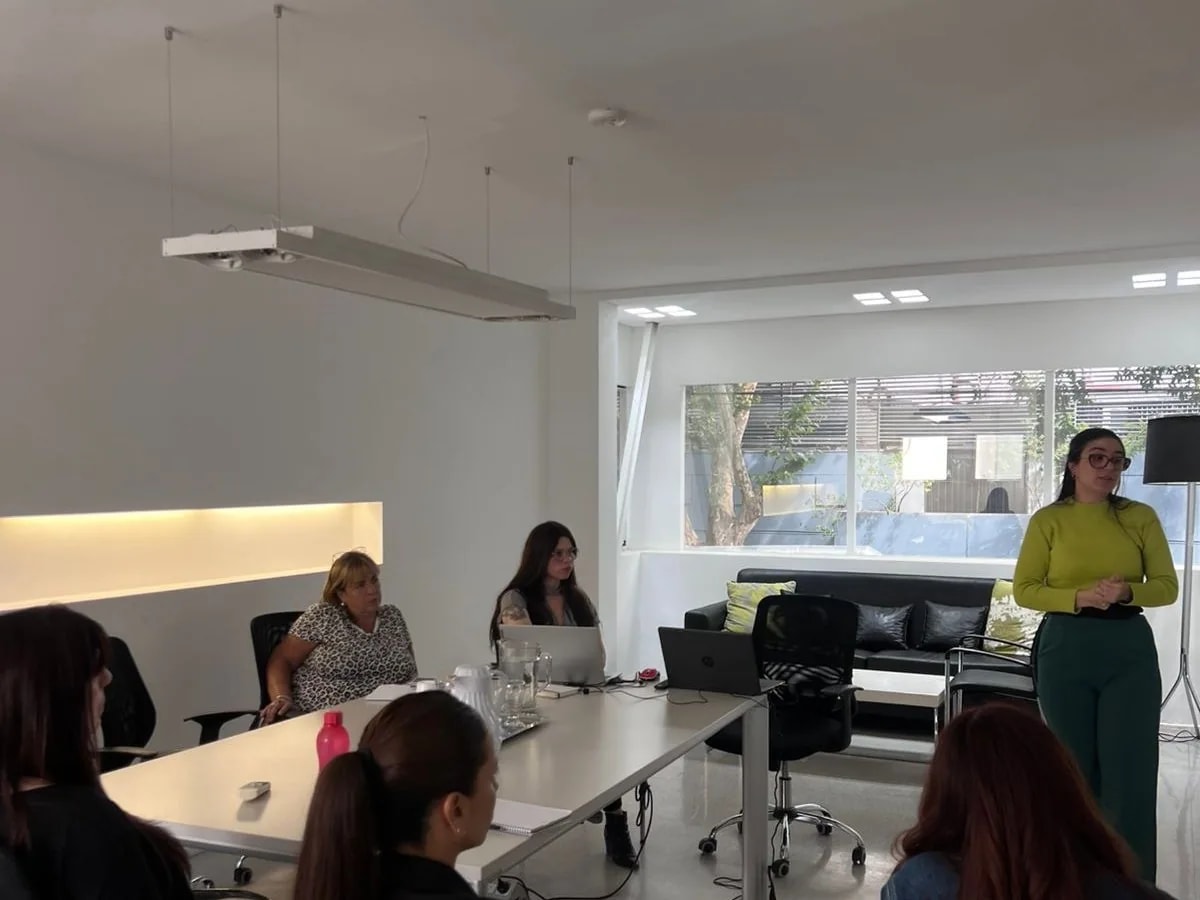 Paula Bria de pie frente a un equipo sentado alrededor de una mesa larga, durante una formación in-company