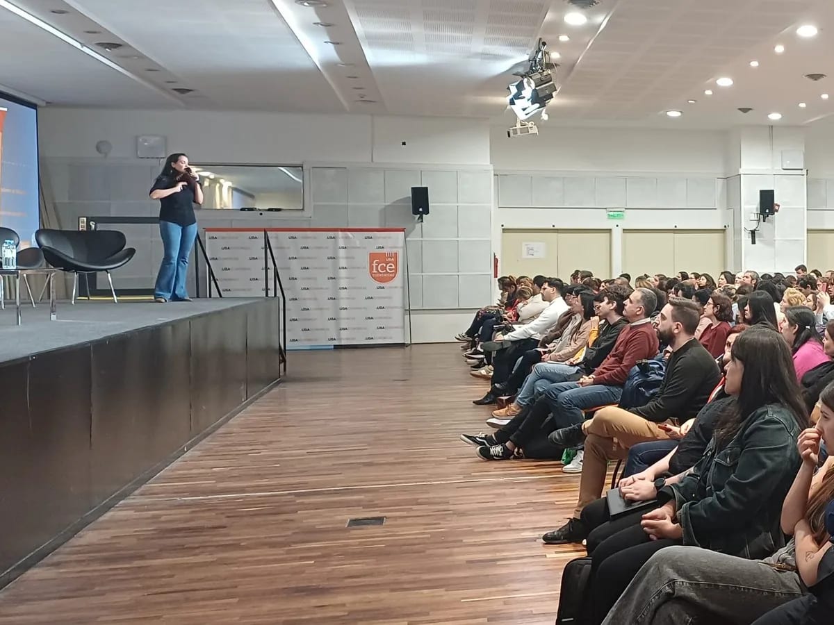 Paula Bria sola en el escenario de un auditorio de la Facultad de Ciencias Económicas de la UBA, ante cientos de personas sentadas