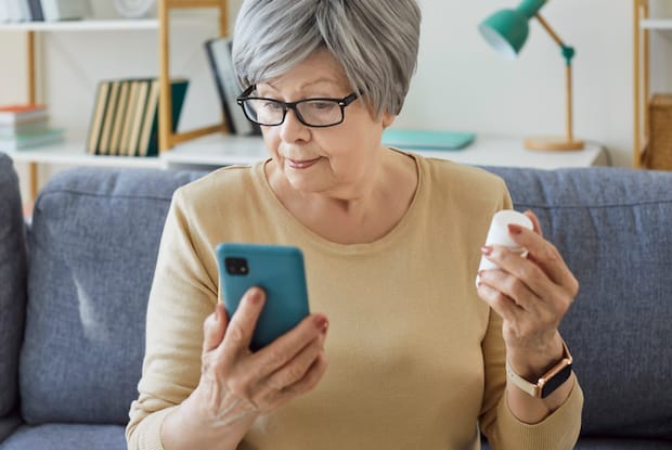 An elderly woman looking up a medication on her phone