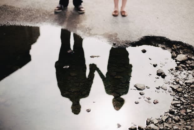 the puddle reflection of a couple holding hands