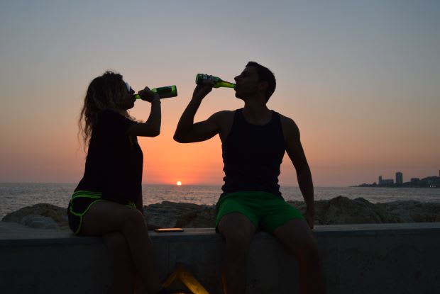 two people drinking beer in the sunset