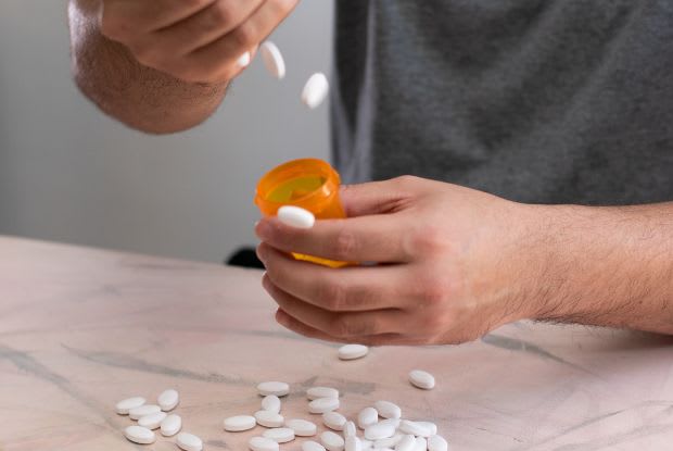 man putting tablets into a medication bottle