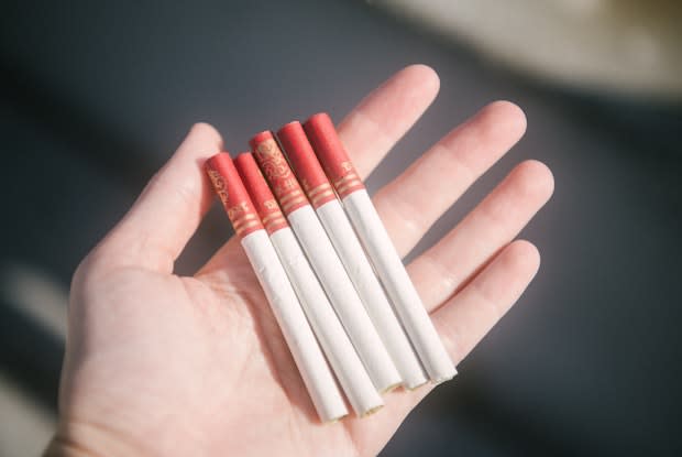 a hand holding several cigarettes