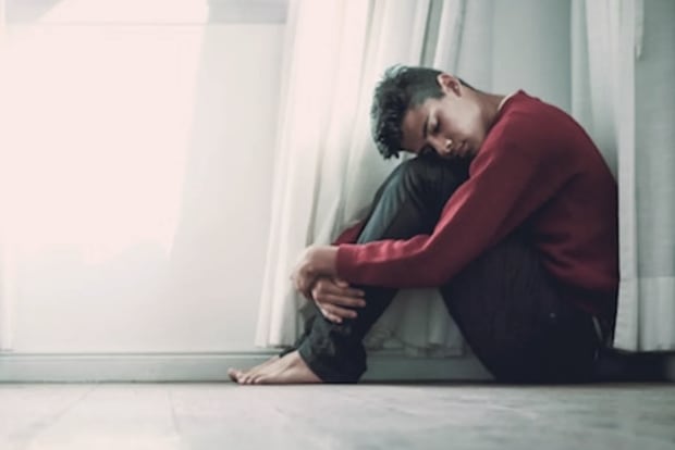 A man sitting on the floor holding his legs