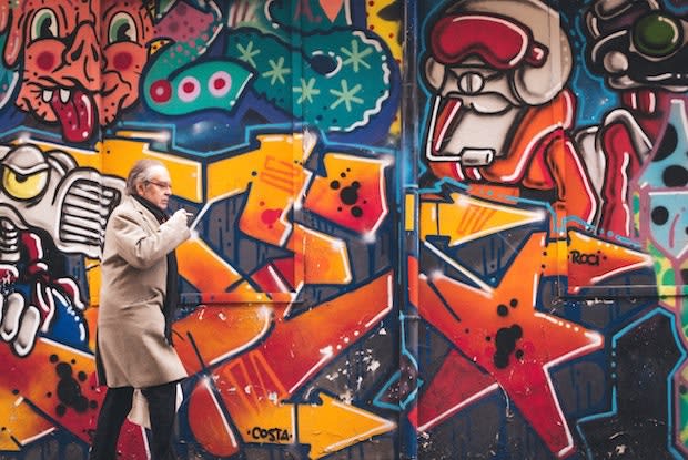 an older man standing in front of a colorful mural