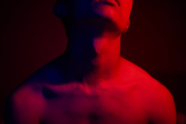 a man’s upper body bathed in red light