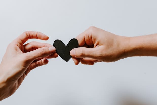 two people holding a paper heart