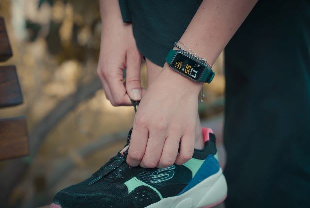 a person, wearing a sports watch, tying their shoelace