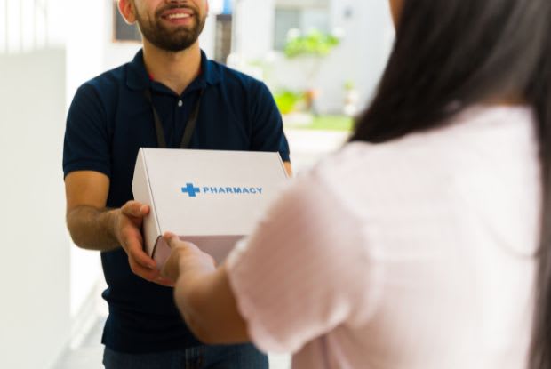 A delivery man delivering a pharmacy package to a woman