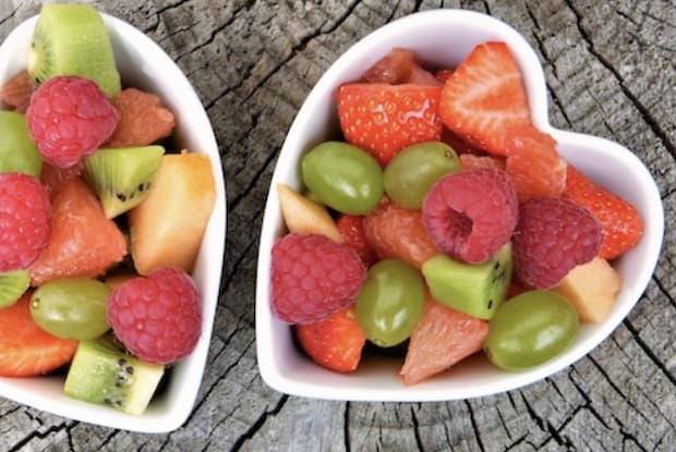 Two heart shaped bowls filled with a variety of fruit