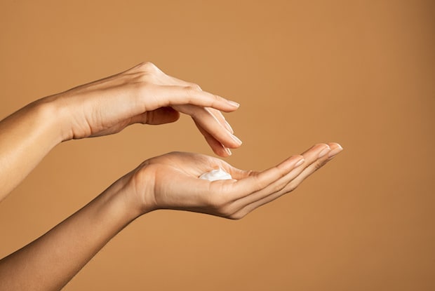 a hand applying cream to the skin