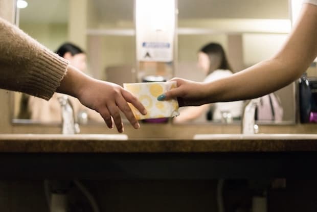 a woman handing another woman an absorbent pad