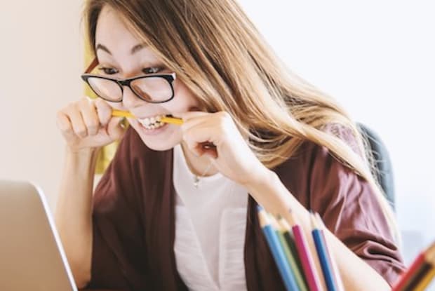 A woman chewing on her pencil as she works