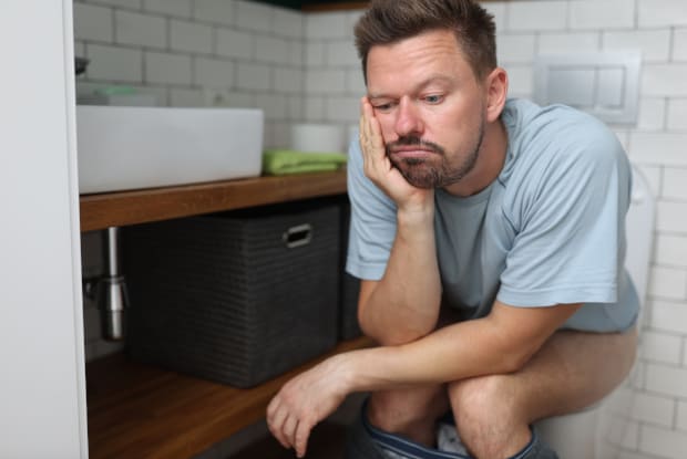 a constipated man sitting on a toilet seat