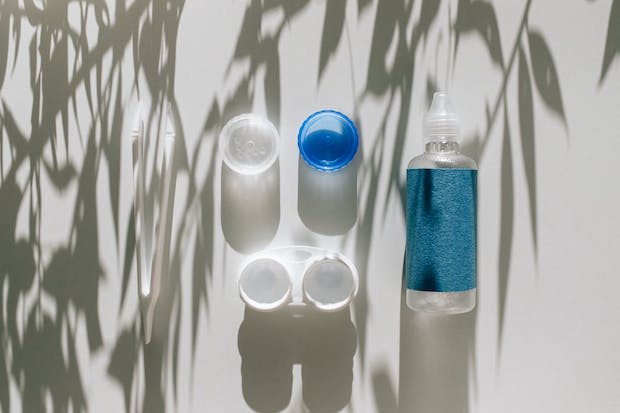 A container for contact lenses next to a bottle of eye drops