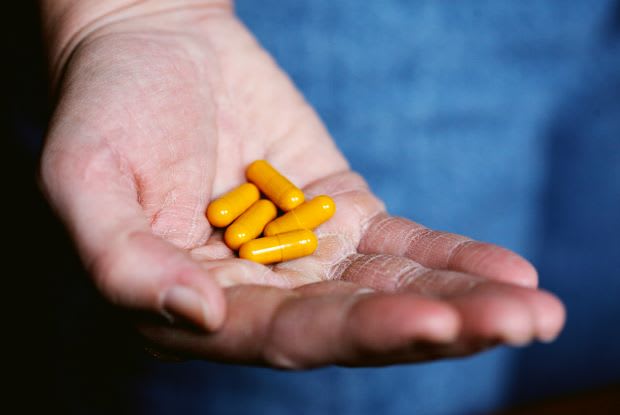 a person holding yellow pills in their hand