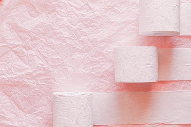 Three rolls of toilet roll on a pink background