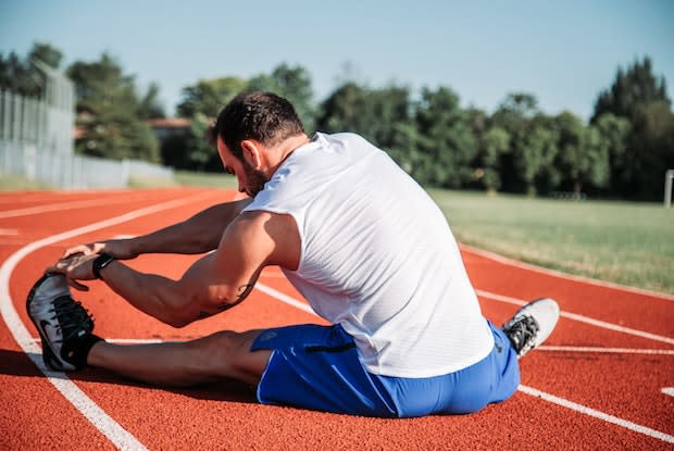 a man stretching on a running track