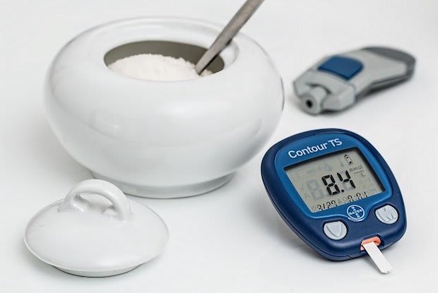 a blood sugar reader next to a bowl of sugar