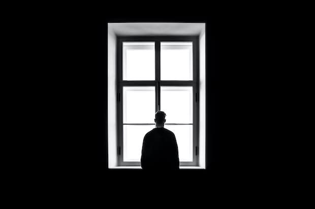 a gray photo of a man standing in front of a window
