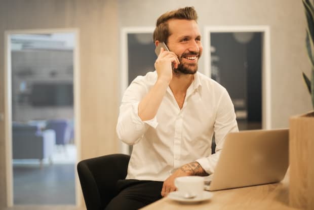 a man smiling while on a phone call