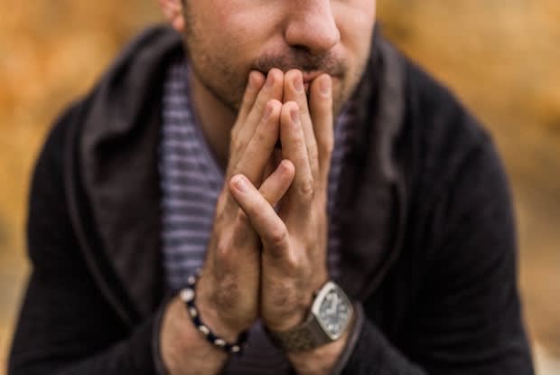 a stressed-looking man putting his hands in front of his face