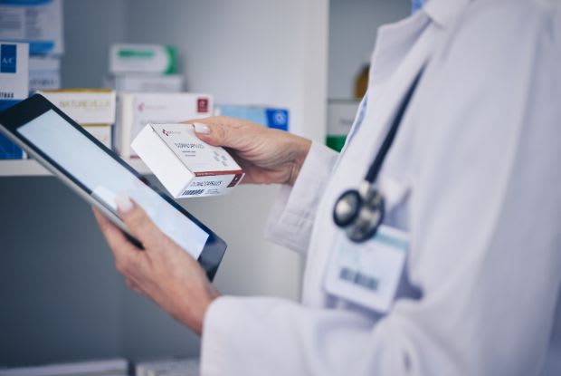 A pharmacist checking medication price on a tablet