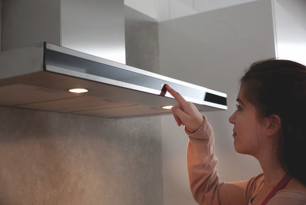 Woman turning on kitchen exhaust