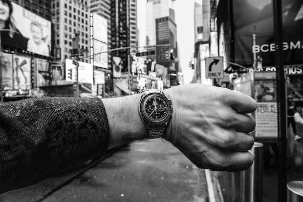 a black and white photo of a man looking at his wristwatch