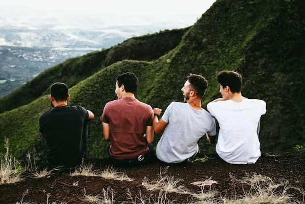 a group of guys sitting together on a hill