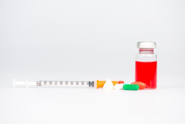 injection vial, syringe, and medication tablets