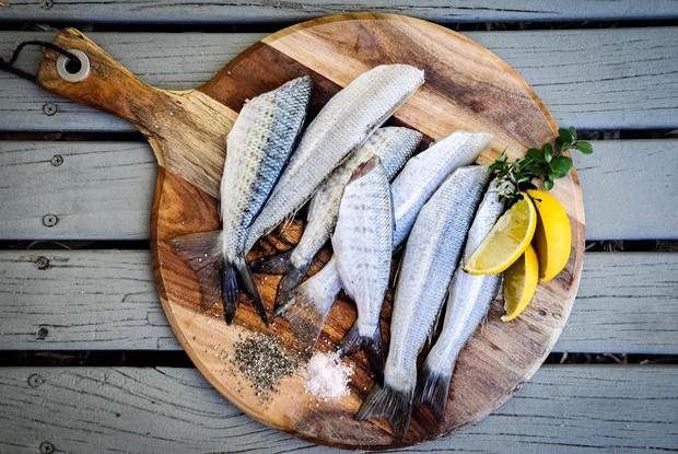 fish on a wood board with lemon wedges