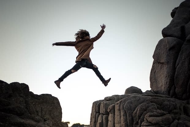 a woman jumping between cliffs, symbolizing risk