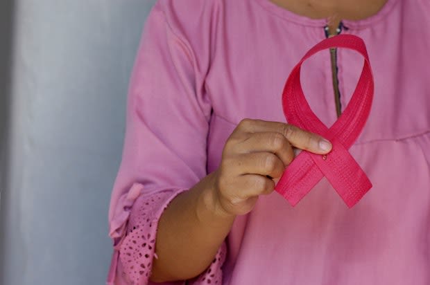 a woman holding a pink breast cancer ribbon